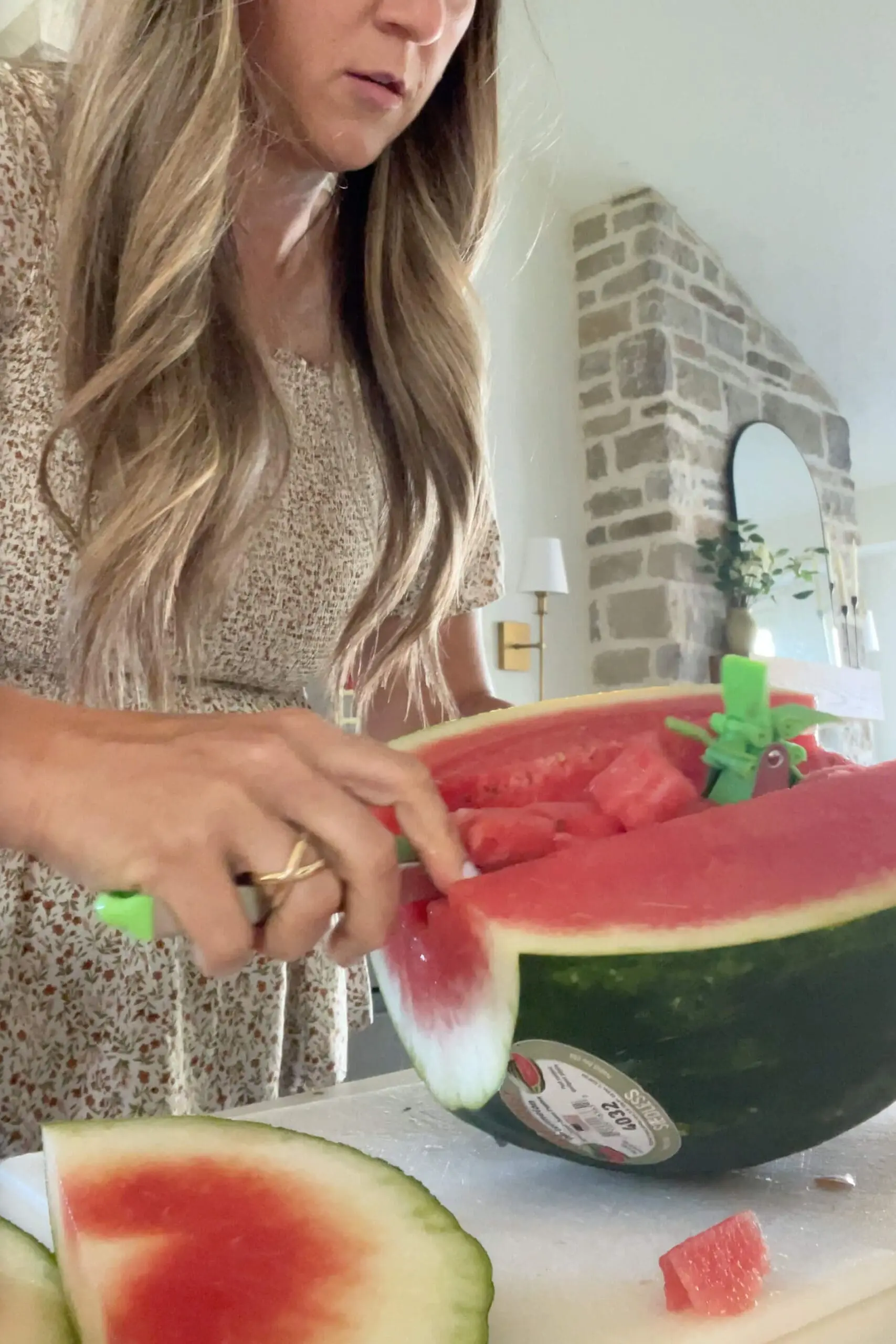 Woman using a rolling watermelon slicer to prep fruit for a backyard get-together—easy summer entertaining tip.